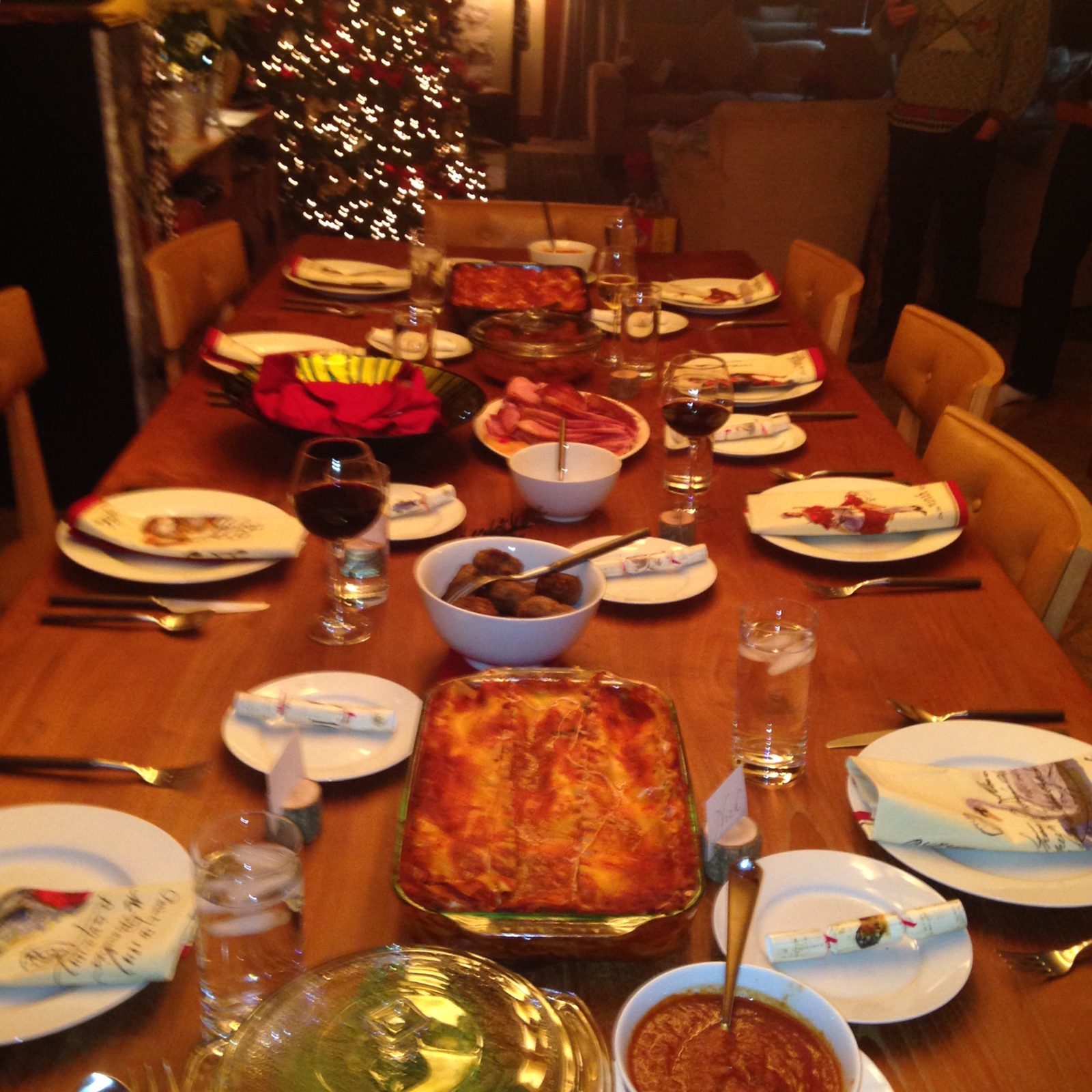 The family table set for a holiday dinner with lasagna, meatballs and place settings